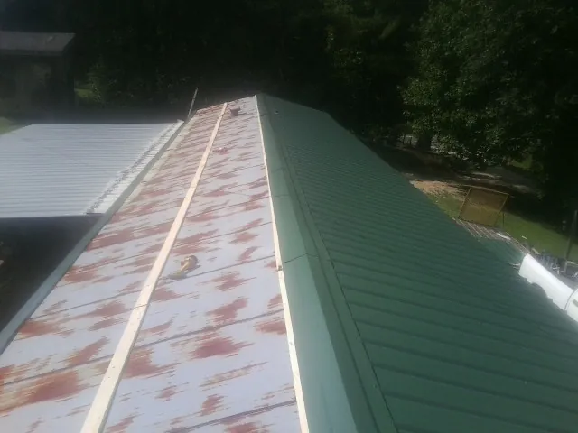 Old rusted panels beside newly installed green metal roofing — Wind Damage Roof Repair by Roofing Brothers in East Bethany