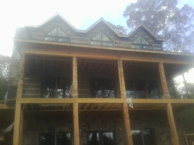 Dormers and porch framing on a large log home under construction — Roof Coating work by our crew in East Bethany