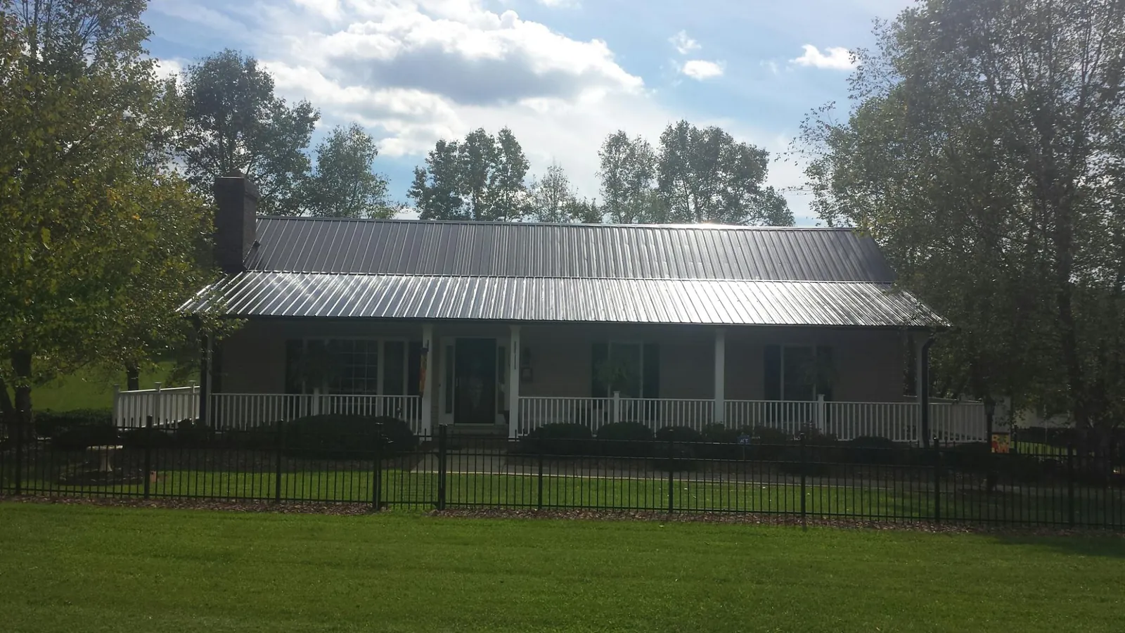 Gray metal roof on a brick ranch with a full width front porch — Gutter Guard Installation work by our crew in East Bethany
