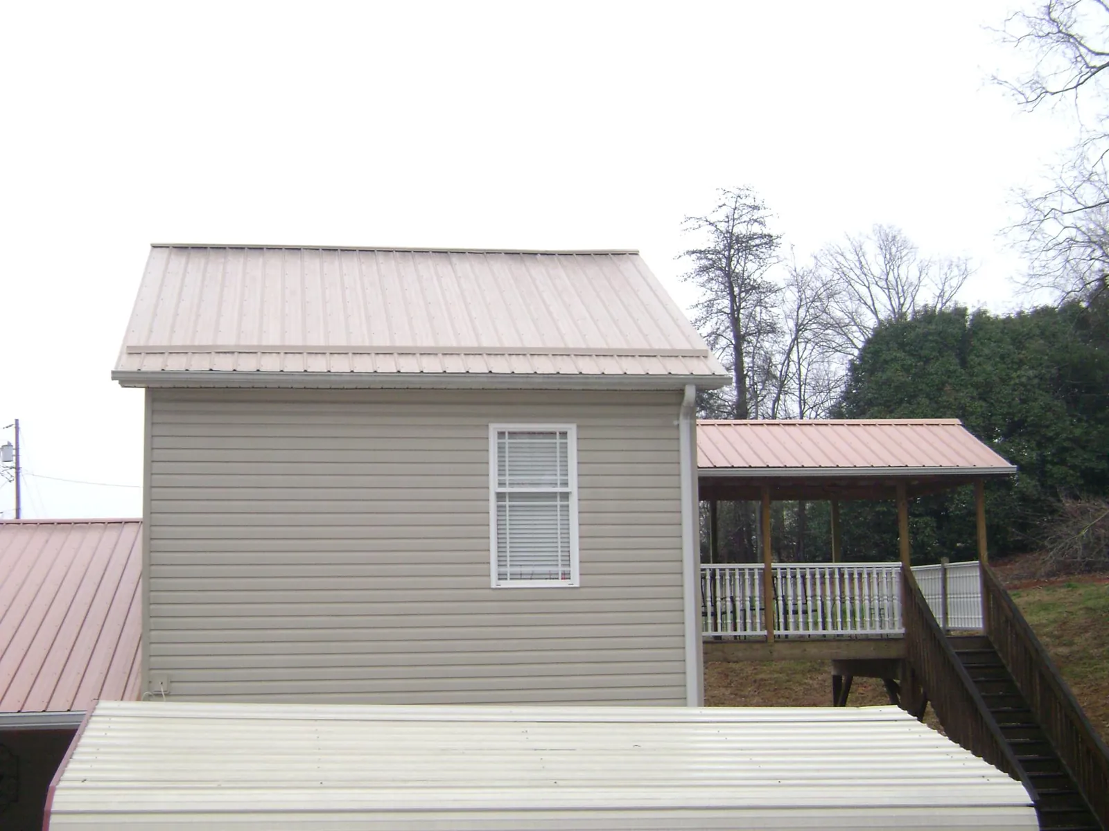 Tan metal roofs on a two story addition and attached porch, from a Roof Replacement job in East Bethany