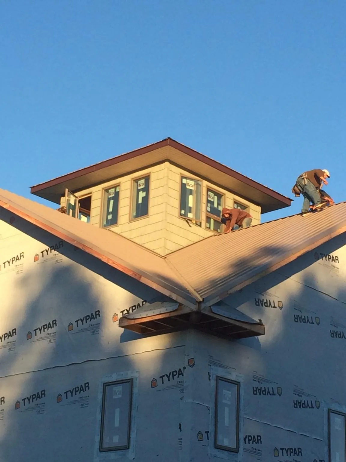 Roofers working around a rooftop cupola on a new metal roof at sunset — Roof Waterproofing in East Bethany by Roofing Brothers